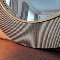 Round mirror with a wooden frame on a wooden surface