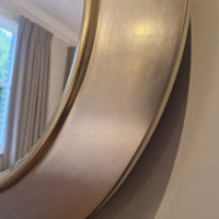Round gold-framed mirror on a wall