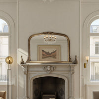 Decorative mirror above a fireplace in a stylish room with arched windows.