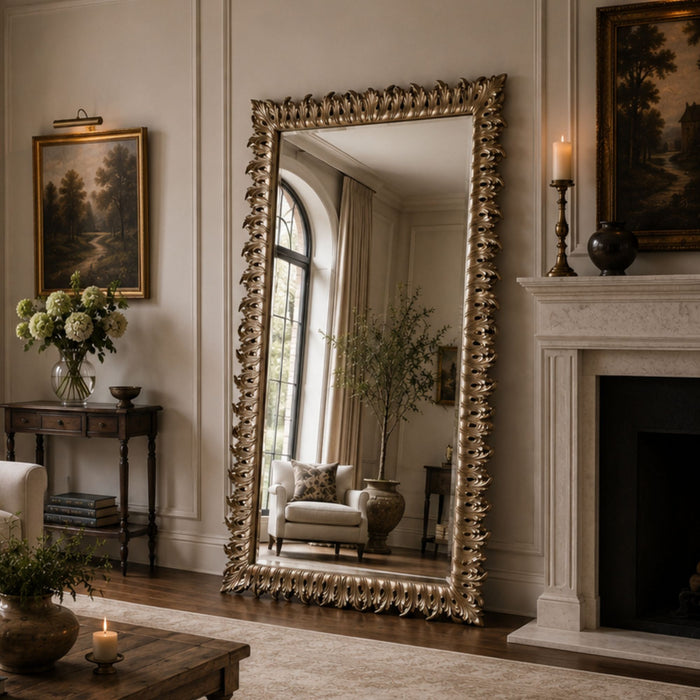 A tall floor mirror with an ornate gold frame stands in a classic living room next to a fireplace and console table.