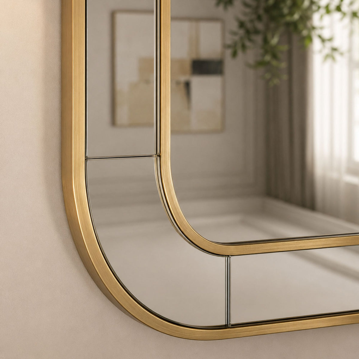 An arched wall mirror with a brushed gold metal frame, shown mounted on a beige wall with its reflection visible.