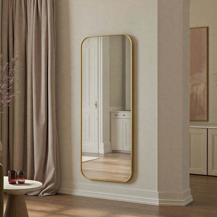 Full-length mirror with gold frame on a wall in a room with curtains and a side table.