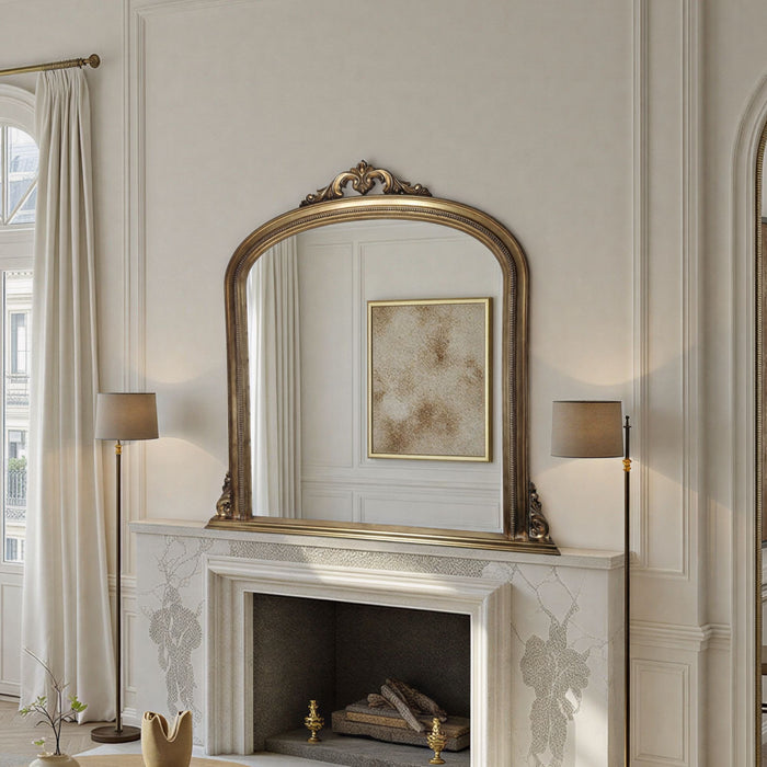 Decorative mirror above a fireplace in a stylish room with lamps and artwork.