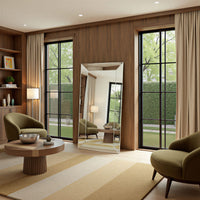 Modern living room with green chairs, a round wooden table, and large windows.