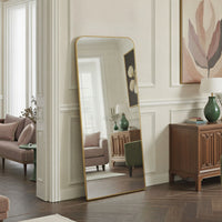 Full-length mirror with gold frame in a living room setting